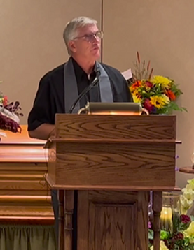 Jeff Sager speaking from a lectern during a funeral service